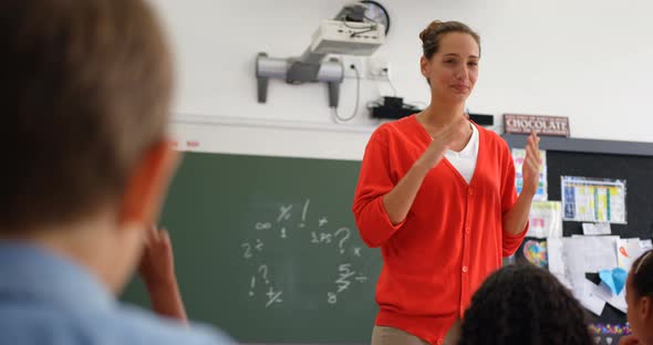 Front view of Caucasian female teacher teaching schoolkids in the classroom 4k