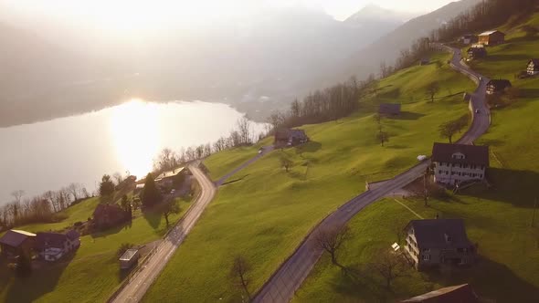 Some cars are driving on a road in Amden, Switzerland while sunset. The camera is turns and tilts to