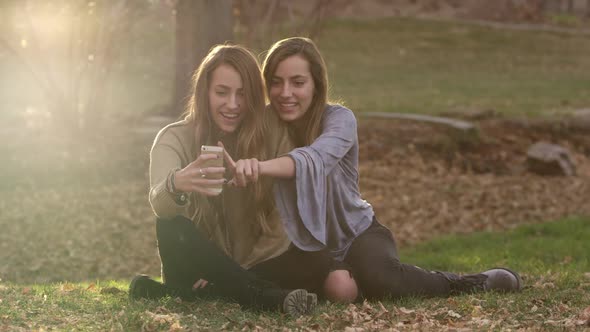 Teenage girl touching smartphone while other holds to take photo