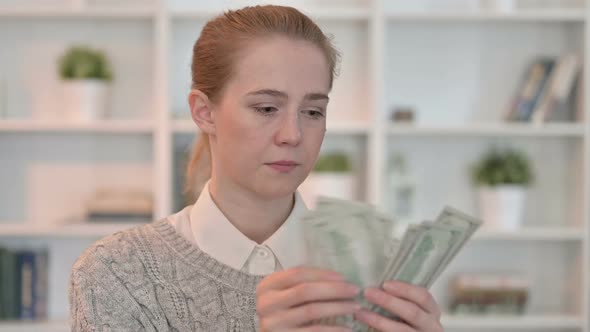 Portrait of Focused Young Woman Counting Dollars