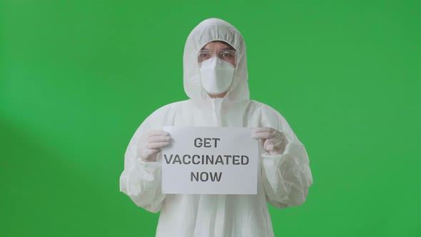 Asian Man Wear Protective Uniform Ppe And Holding Get Vaccinated Now Sign In The Green Screen Studio