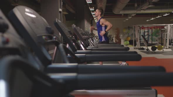 Bodybuilder running on treadmill at gym