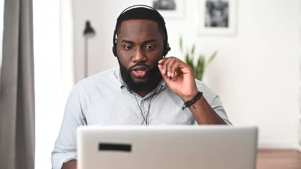 An African American Guy is Using Headset and Laptop for Work