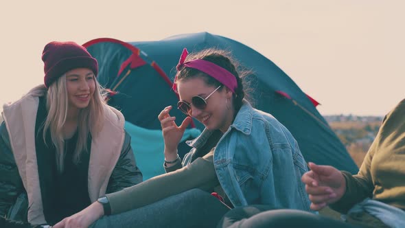 Positive Women Hikers Rest Talking at Tent in Warm Evening