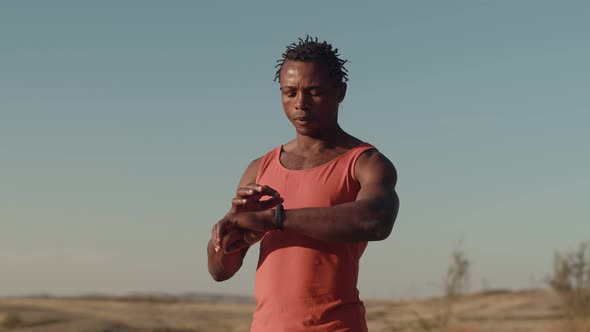Black Male Athlete Looks at the Watch and Starts Running