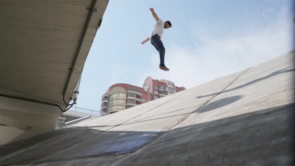 Male Athlete Jumps on a Slope and Slides Down on Bright Sunny Day