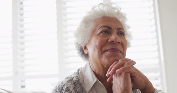 Close up of african american senior woman with hand on chin smiling at home
