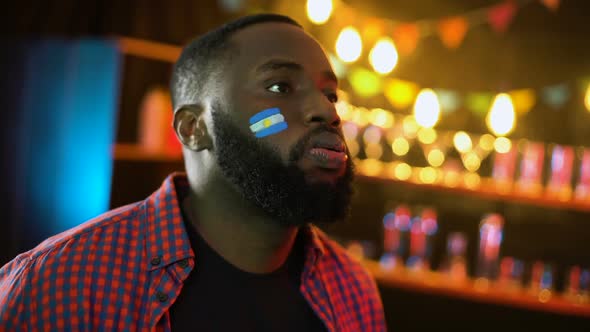 Emotional Black Football Fan With Argentinian Flag on Cheek Making Facepalm