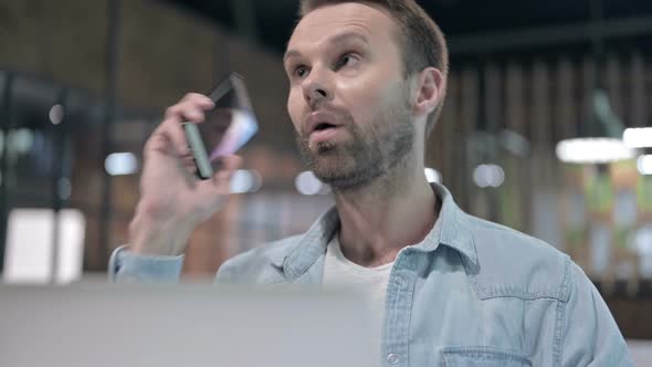 Close Up of Positive Young Man Talking on Phone at Work