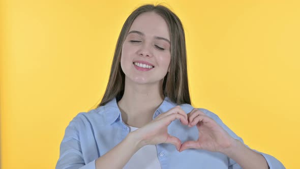 Heart Shape with Hand By Casual Young Woman, Yellow Background