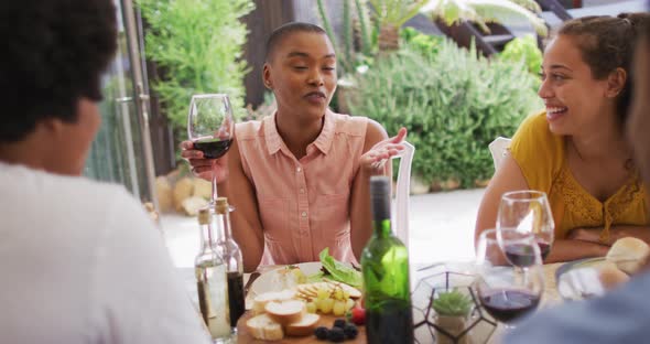 Happy african american woman talking with friends at dinner party on patio