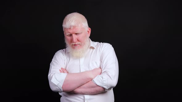 Man with Albinism Who Is Serious with His Hands Folded and Looking Down.