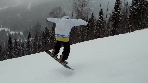 Slow Motion of a Male Snowboarder Jumping on a Slope