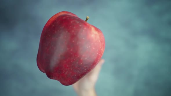 Throwing Up and Catching Red Apple Above Table Surface