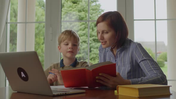 Young 30s Mother Reading Funny Book to Her Son at Home