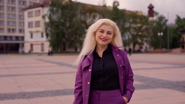 Portrait of joyful young woman standing alone at street smiling looking at camera. Attractive female