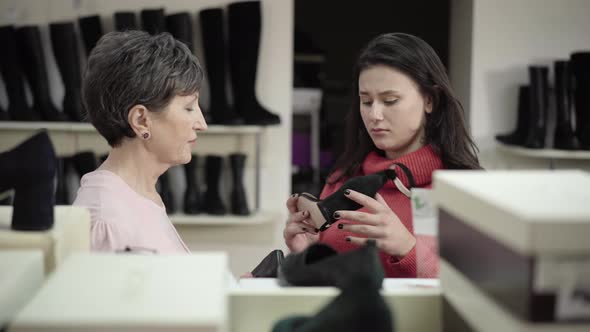 Senior and Young Women Discussing Shoes in Shop. Portrait of Confident Caucasian Buyer and Seller