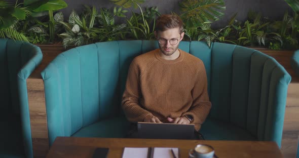 Top View of Man Who Sits in Cafe in Daytime and Using the Laptop for the Remote Work