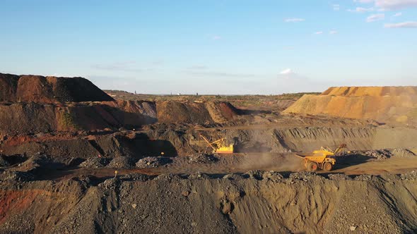 Large Mining Dump Truck Driving on a Dusty Road at the Sunset