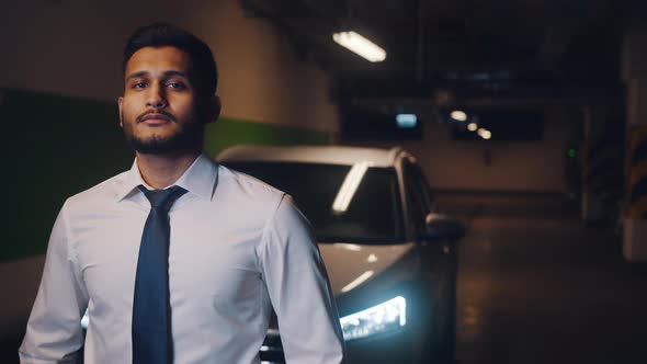 Indian Businessman Standing in the Parking Lot with Serious Facial Expressions