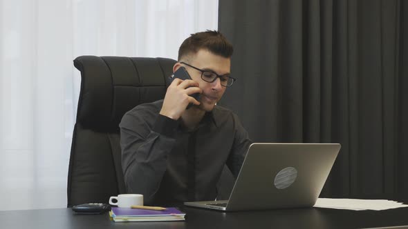 Successful businessman talking on phone sitting at his office desk