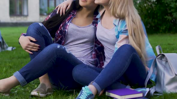 Best Female Friends Sitting on Grass, One Hugging Another by Shoulder, Support