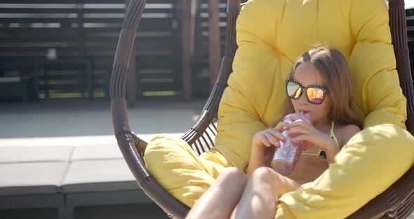 Little Girl in Sunglasses Enjoy Drink in Chair
