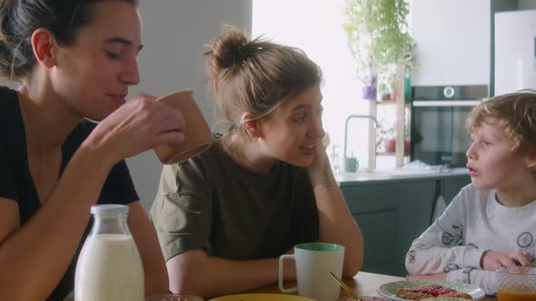 Little Boy Talking with Lesbian Parents during Meal at Home