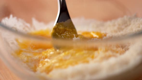 Camera follows mixing eggs with bread crumb in a bowl. Slow Motion.