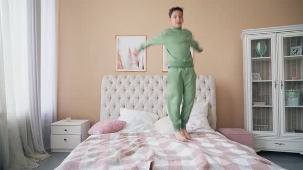 Caucasian Boy Jumping on Bed Having Fun Laughing Playing Funny Active Game with Cute Child Son in