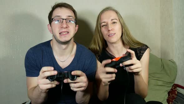 Guy And Girl Are Playing On The Console Using Gamepads