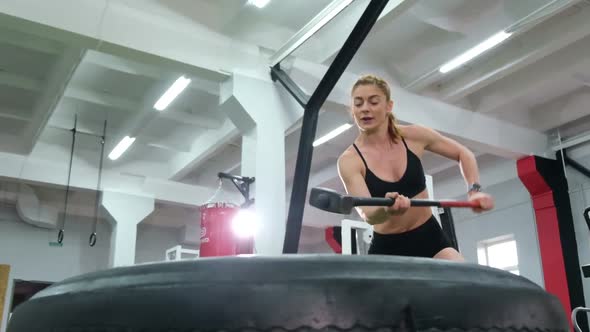 The girl is engaged in crossfit. Beats with a hammer in training.