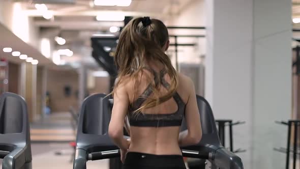 sportswoman running on a treadmill, view from the back