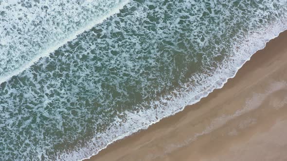 Aerial view of waves crash to beach