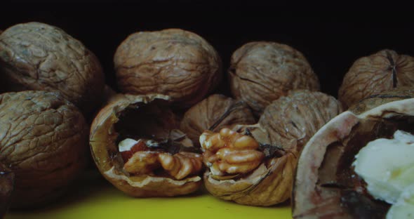 Closeup Shot of Walnuts Which Lie on a Yellow Table Against a Black Background