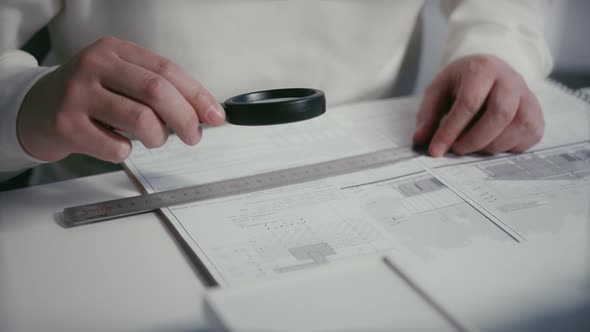 Architect or engineer reviewing with a magnifying glass the measurements on the foundation plans of