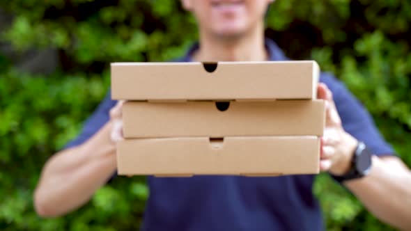 Pizza Delivery Boy Holding Pizza Boxes in House Garden in Front of Door