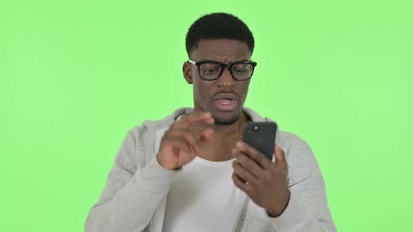 African Man Loss on Smartphone on Green Background