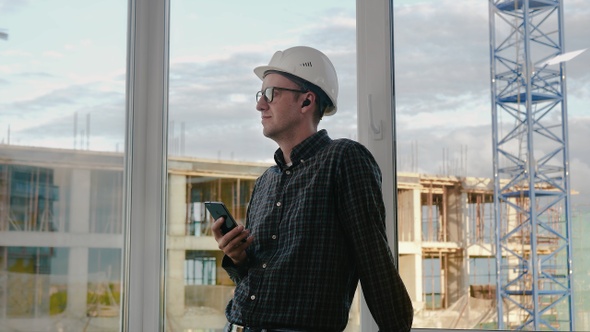 Construction worker listening to music from his phone with