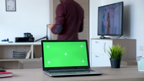 Laptop with a Green Screen on It in Living Room