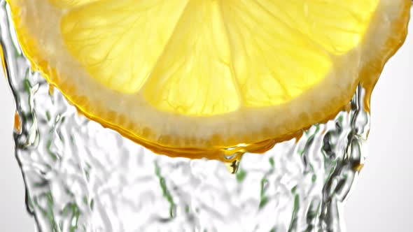 Super Slow Motion Macro Shot of Flowing Water From Lemon Slice on White Background at 1000Fps