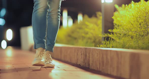 Closeup Legs in Sneakers are Walking Along the Sidewalk Along the Street