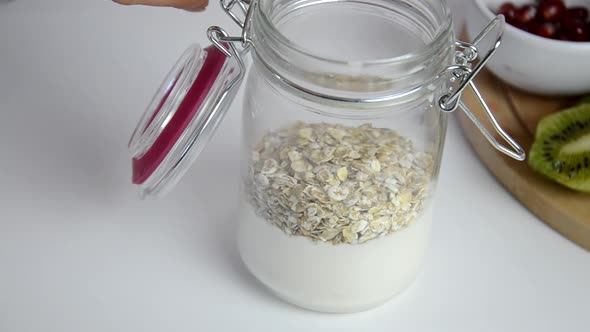 Girl makes Healthy breakfast overnight oats with fresh berries in a glass jar