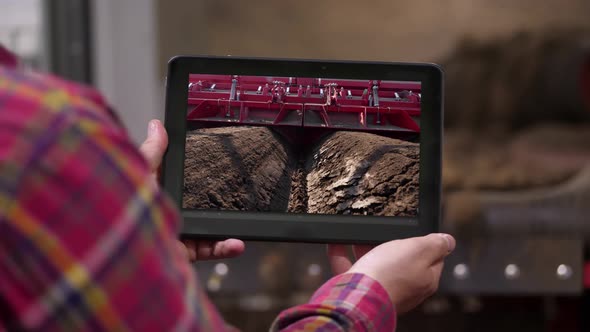 Close-up, Farmer Holds Digital Tablet in Hands on Background of Potato Storage Warehouse. It Shows