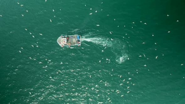 Aerial view of fishing boat in turquoise sea Mevagissey.