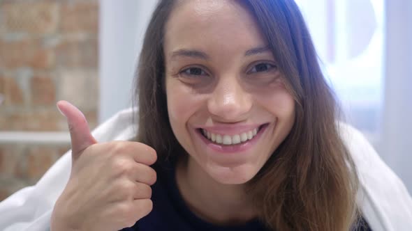 Thumbs Up by Excited Hispanic Woman in Bed