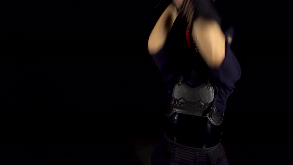 Strong Kendo Guru Practicing Martial Art with the Bamboo Bokken on Black Background.