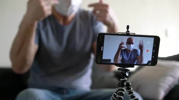 Bald Male Blogger in Medical Mask Recording Video Talking Using Smartphone