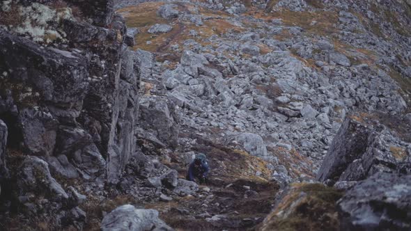 Hiker Clambering Hillside Rocks