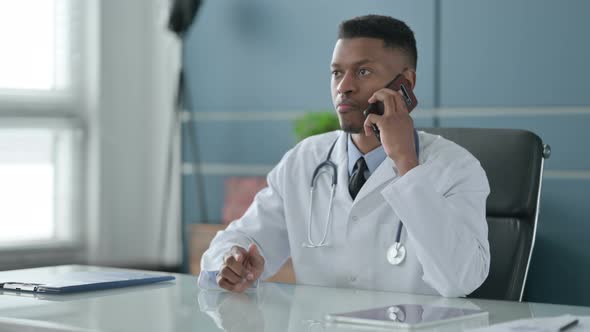 African Doctor Talking on Smartphone in Office